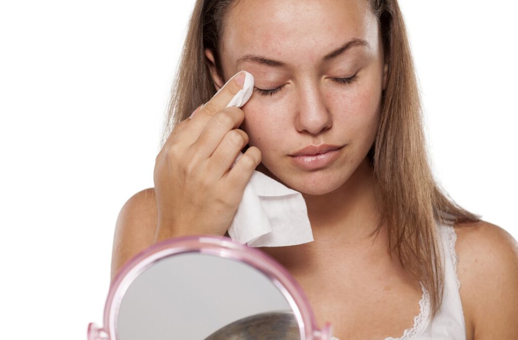 Young woman cleansing her eye lids with wet wipes.