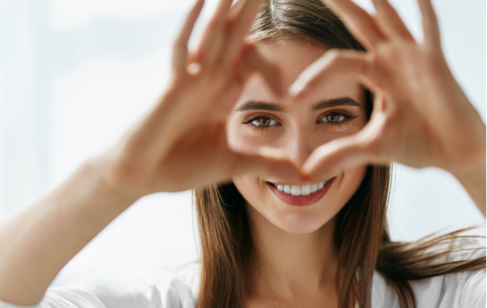 Women forming love sign close to her eyes to show healthy eyes and vision