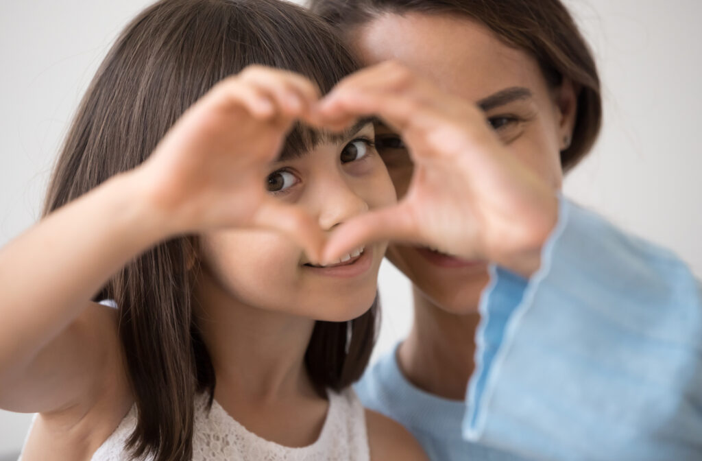 Mother and daughter creating heart around eye to portray healthy eyes