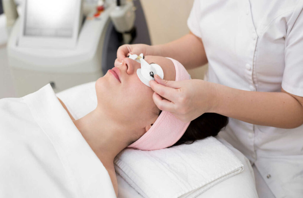 A person placing protective eyewear over a patient's eyes before starting an IPL treatment.