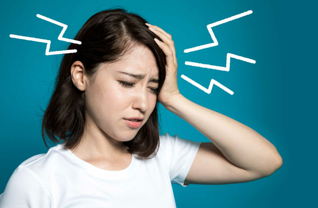 A woman holding her head as she experiences severe headache due to dry eye.