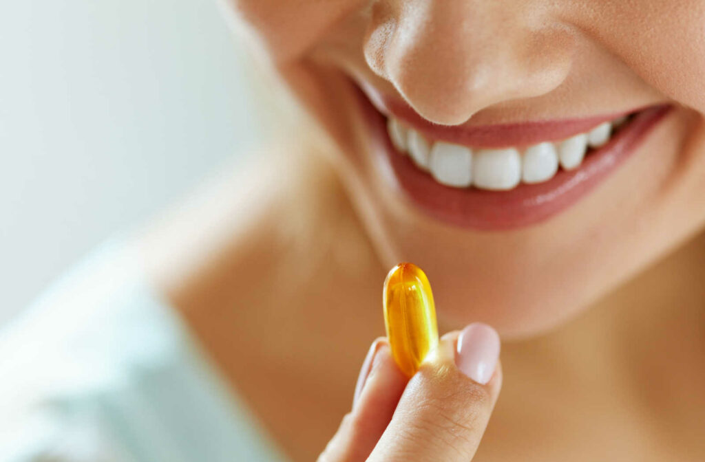 A close-up of a woman with beautiful smile taking omega 3 supplement.