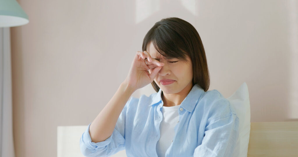 A young woman rubbing her eyes vigorously due to an irritation in the eye caused by blepharitis.