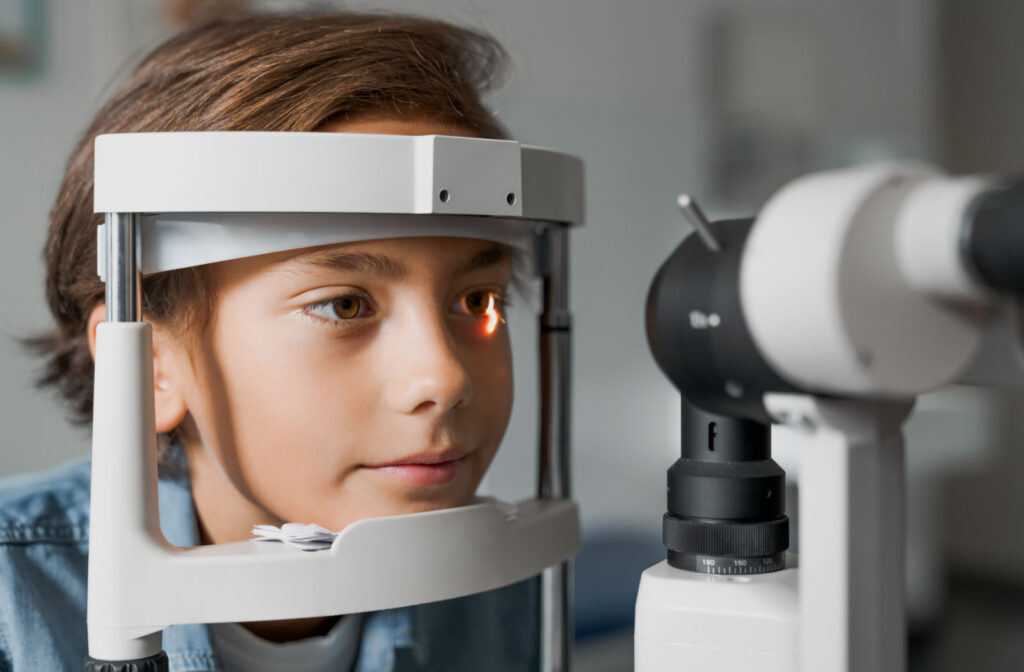 A child sitting in an optometrist office looking into a machine that tests his vision