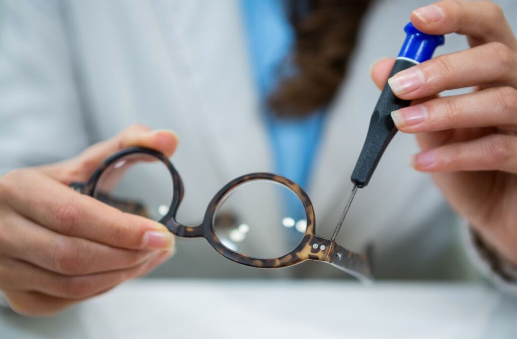 An optician using a tool to fix a pair of glasses.