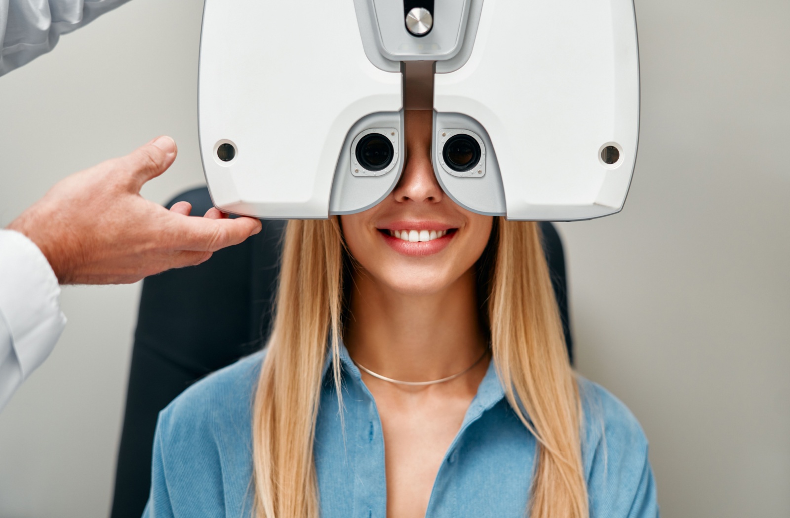 A woman sitting behind a phoropter during an eye exam.