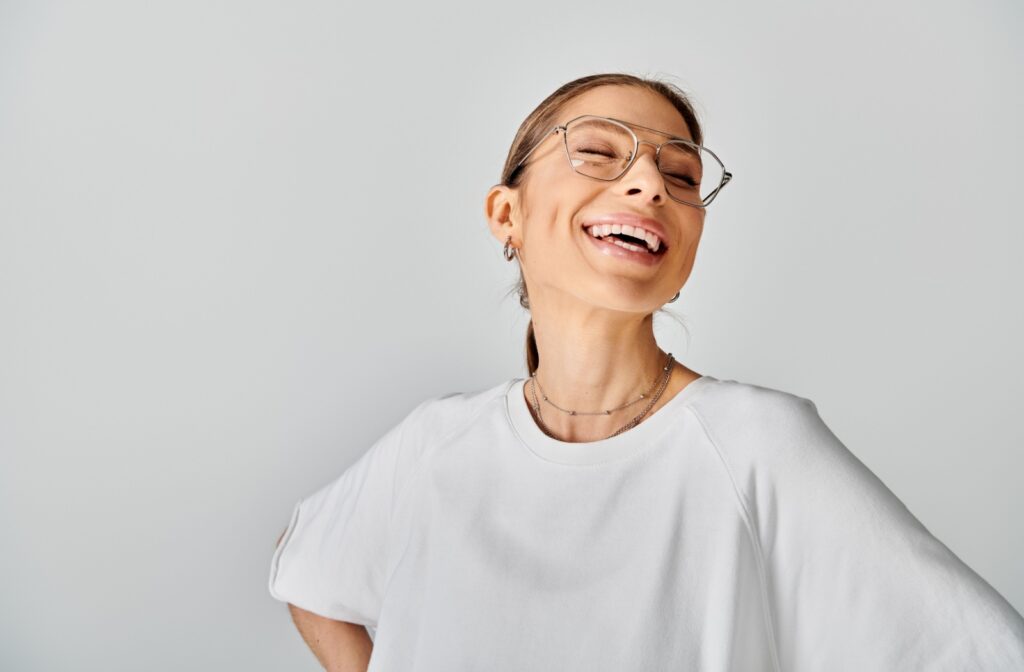 Smiling woman wearing prescription glasses, representing clear vision after a comprehensive eye exam.