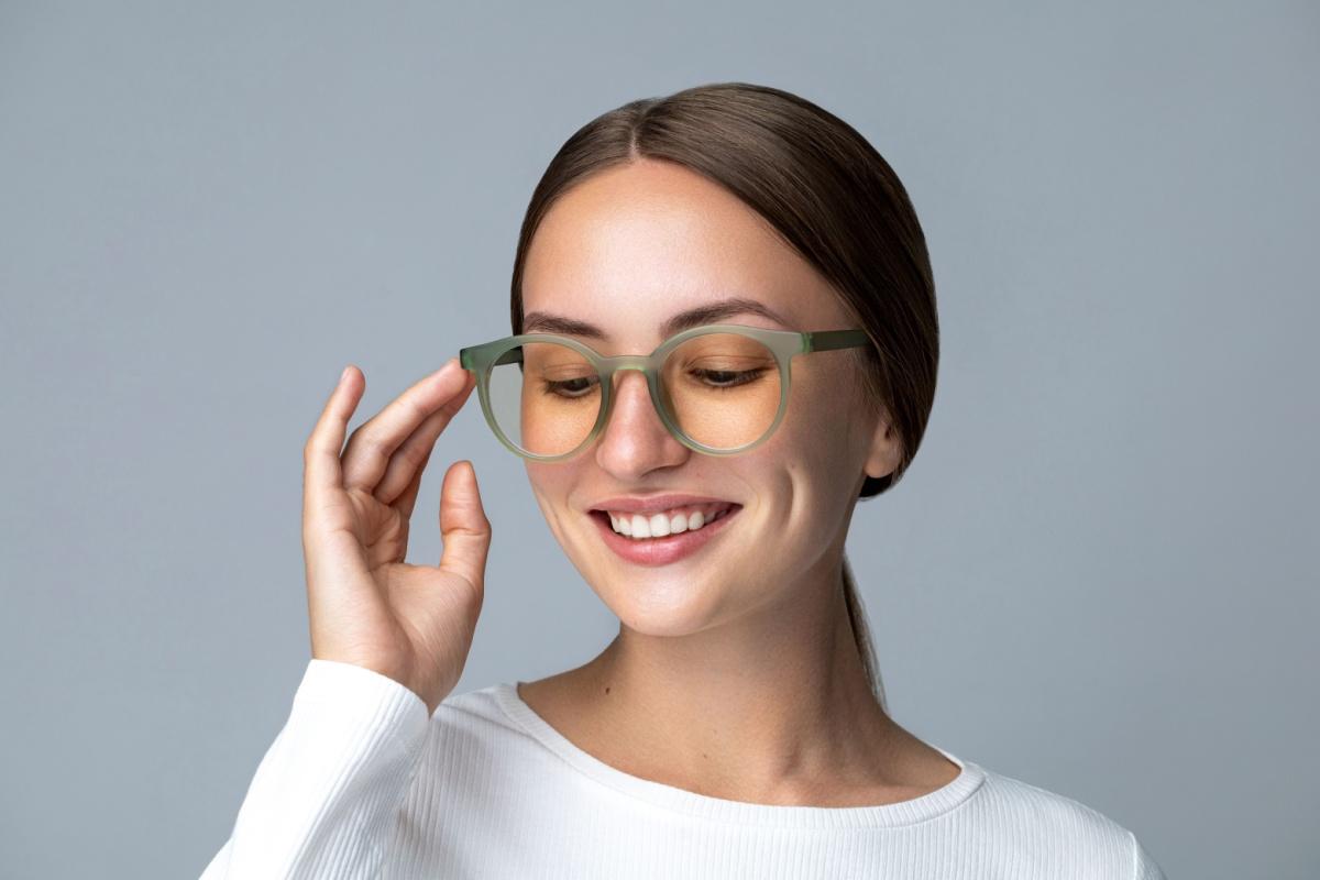 Smiling woman putting her hand to her designer glasses frames.